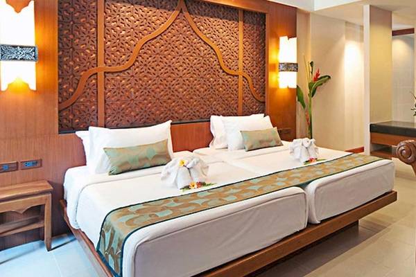 Doppelbettzimmer im Rawai Palm Beach Resort mit zwei Betten, Dekor und Möbeln.