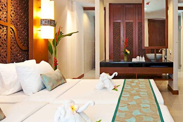 Hotelzimmer im Rawai Palm Beach Resort mit zwei Betten, Dekor und Möbeln.