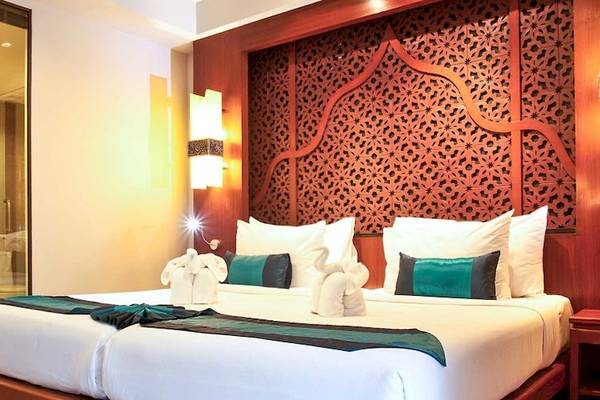 Doppelbettzimmer im Rawai Palm Beach Resort mit rotem Dekor und zwei weißen Kissen.