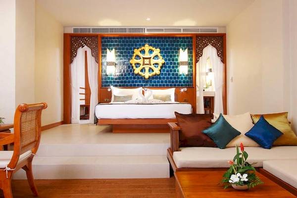 Innenansicht eines Zimmers im Rawai Palm Beach Resort mit Bett, Fernseher und Wohnzimmer