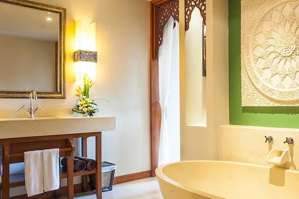 Badezimmer im Rawai Palm Beach Resort mit Badewanne, Waschbecken und Spiegel.