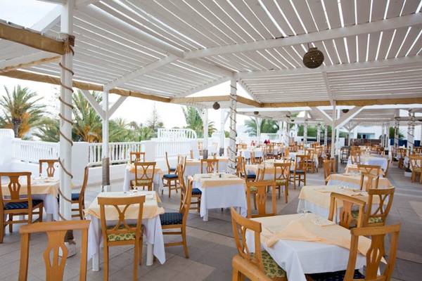 Terrasse des El Mouradi Djerba Menzel Hotels mit gedeckten Tischen und Stühlen.
