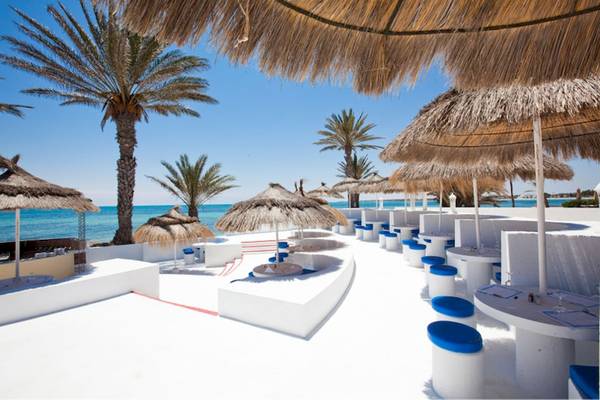 Terrasse des El Mouradi Djerba Menzel Hotels mit Sonnenschirmen und Tischen am Meer