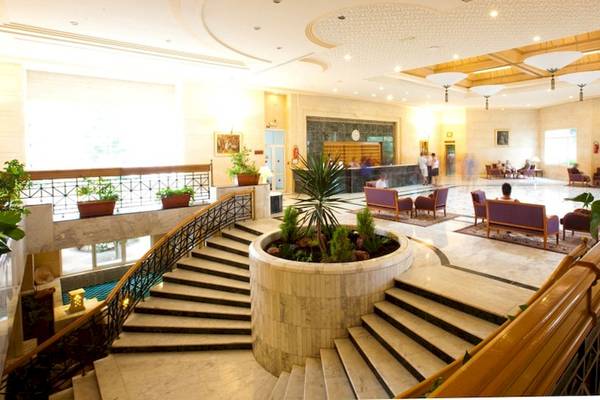 Lobby des El Mouradi Djerba Menzel Hotels mit zentraler Pflanze und Treppen.