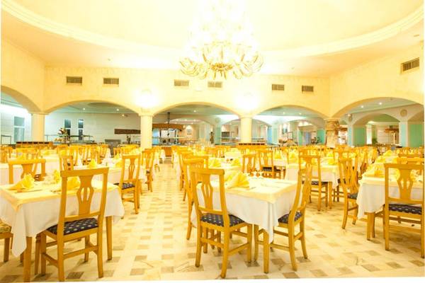 Ein großes Speisesaal des El Mouradi Djerba Menzel Hotels mit vielen gelben Stühlen und Tischen.