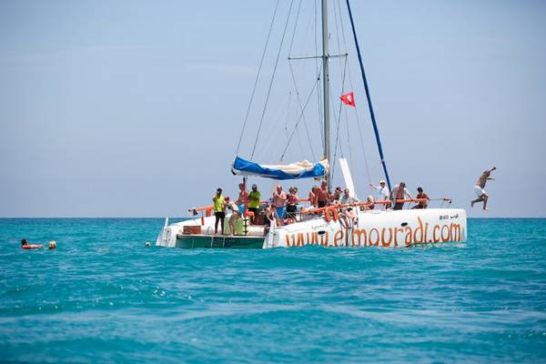 Katamaran mit Urlaubern im Meer, Webseite von El Mouradi Djerba Menzel sichtbar