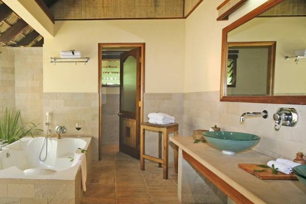 Badezimmer im Cerf Island Resort mit Badewanne, Dusche, Waschbecken und Spiegel.