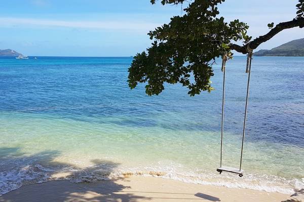 Ein Schaukel am Strand des Cerf Island Resorts mit Blick auf das blaue Meer und die Berge