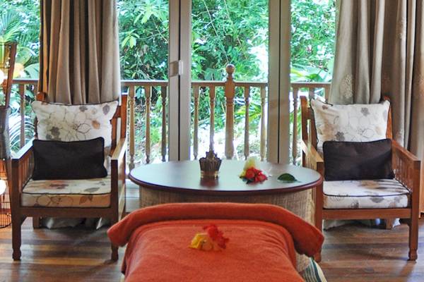 Luxuriöses Hotelzimmer mit Balkon, zwei Sesseln, Tisch und Liege.
