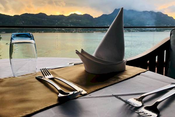 Tisch mit Besteck und Getränk auf Balkon mit Ausblick auf Meer