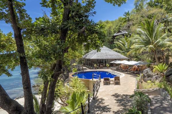 Außenbereich des Cerf Island Resort mit Pool, Lounge-Stuhl und Sonnenschirmen