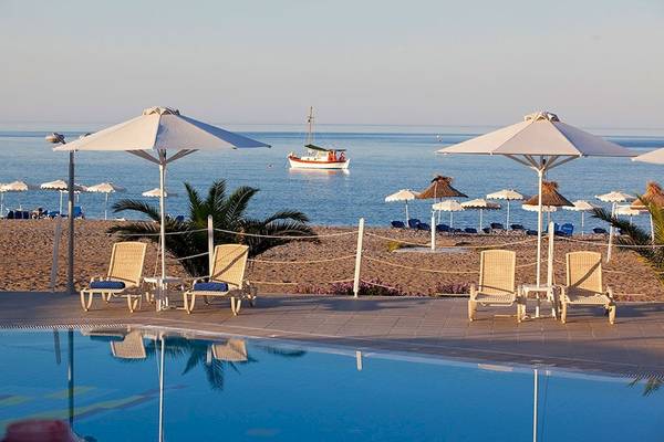 Außenbereich des Lindos Bay Hotels mit Pool, Liegestühlen und Sonnenschirmen am Strand