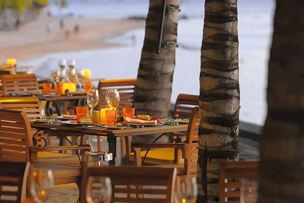 Restaurant am Strand des Victoria Beachcomber Resorts mit gedeckten Tischen und Palmen