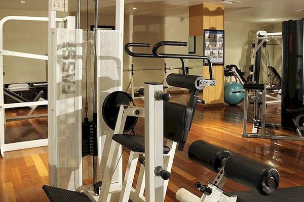 Fitnessstudio im Victoria Beachcomber Resort & Spa mit verschiedenen Trainingsgeräten auf einem hölzernen Boden.