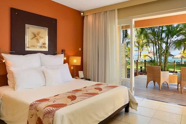 Ein modernes Hotelzimmer mit Blick auf eine Terrasse und den Ozean, Victoria Beachcomber Resort & Spa.
