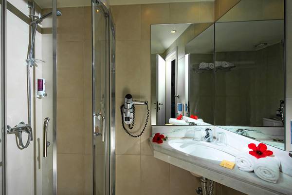 Badezimmer im Silva Beach Hotel mit Glasdusche, Handtuchtrockner und Spiegel.