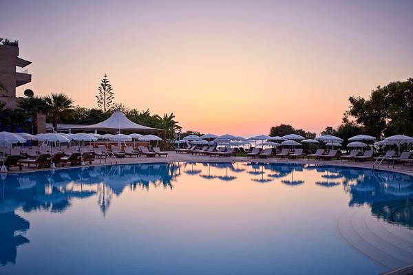 Außenpool des Grecian Park Hotels bei Sonnenuntergang mit vielen Sonnenliegen und Schirmen