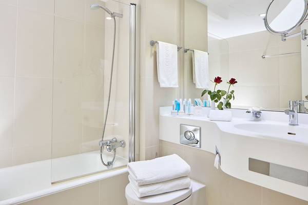 Badezimmer im Grekischen Park Hotel mit Badewanne, Dusche, Toilette, Waschbecken und Spiegel.