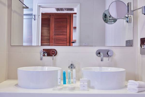 Badezimmer im Grecian Park Hotel mit Doppelwaschbecken und Spiegeln