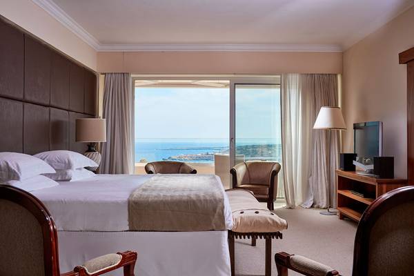Griechenland Park Hotelzimmer mit Meerblick, komfortables Bett, zwei Stühle und Fernseher.
