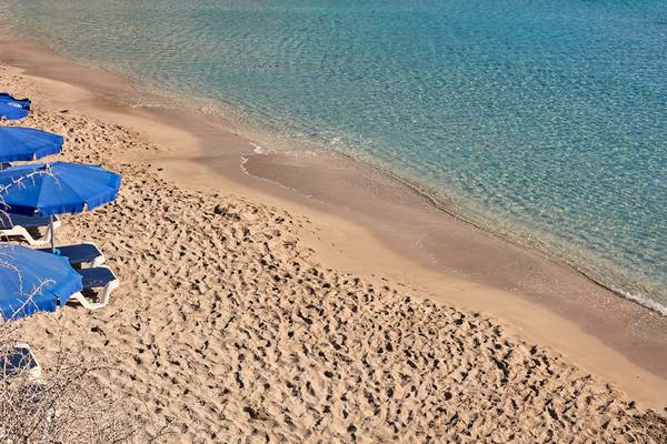 Strand des Grecian Park Hotels mit blauen Sonnenschirmen und kristallklarem Wasser