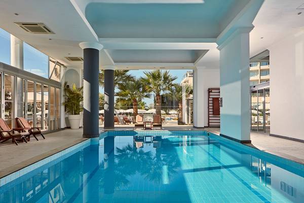 Innenpool des Grecian Park Hotels mit Loungemöbeln und Palmen im Hintergrund