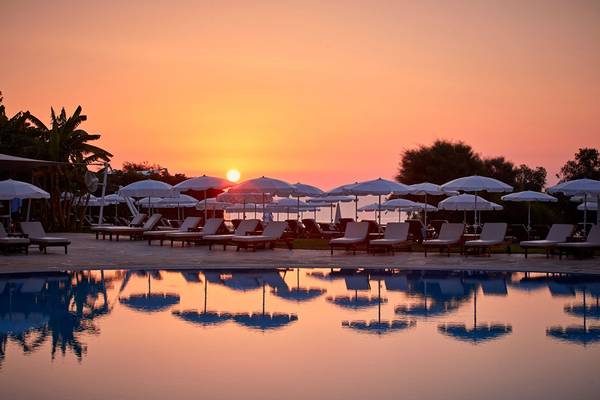 Sonnenuntergang am Pool des Grecian Park Hotels mit vielen Sonnenschirmen und Liegestühlen.