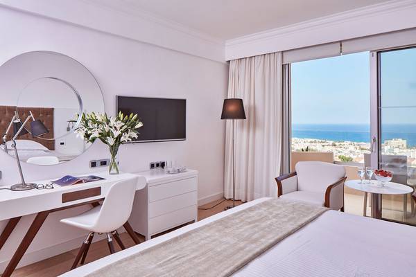 Griechischer Park Hotelzimmer mit Meerblick, Bett, Schreibtisch und Balkon.