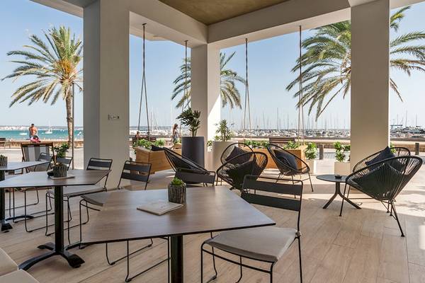 Außenbereich des Las Arenas Hotels mit Tischen, Stühlen und Blick auf das Meer.
