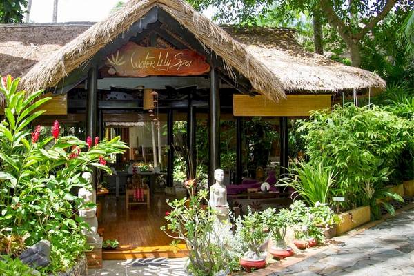 Eingang des Bamboo Village Beach Resort & Spa mit einem strohgedeckten Dach und tropischen Pflanzen.