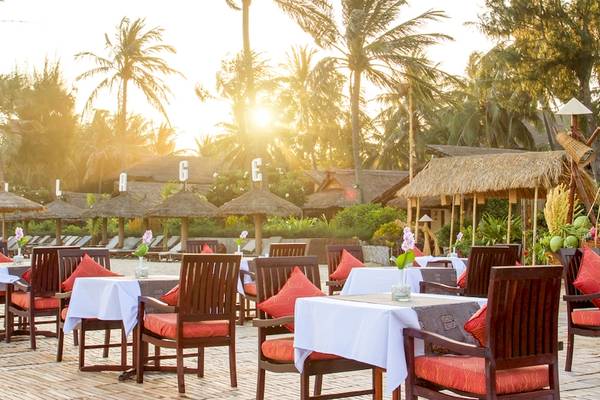 Außenterrasse des Bamboo Village Beach Resort mit Tischen und Stühlen im Sonnenuntergang