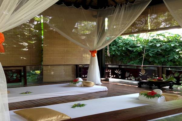 Massage-Behandlungsraum im Bamboo Village Beach Resort & Spa mit zwei Liegen, weißen Tüchern und Dekorationen.