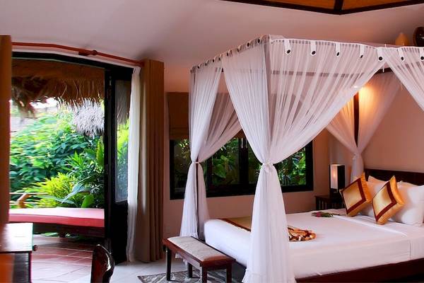 Schlafzimmer im Bamboo Village Beach Resort & Spa mit Himmelbett und Blick auf den Garten.