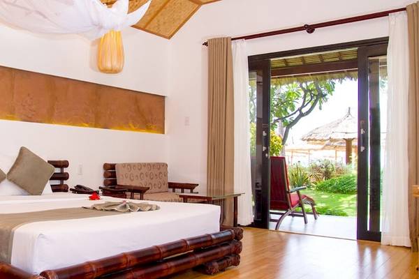 Schlafzimmer im Bamboo Village Beach Resort & Spa mit Bambusbett und Terrassentür.