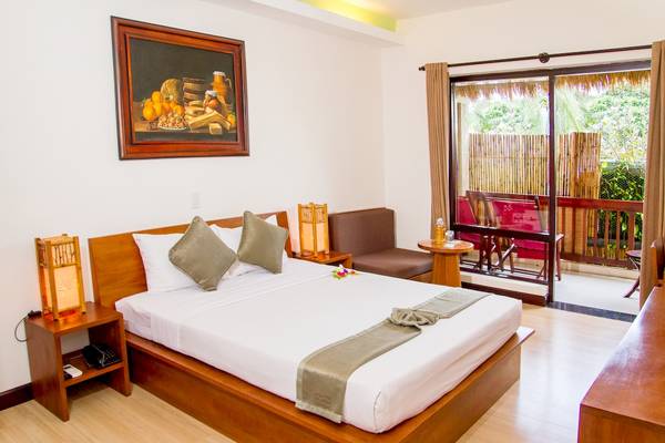 Hotelzimmer im Bamboo Village Beach Resort mit Bett, Möbeln und Blick auf den Balkon.