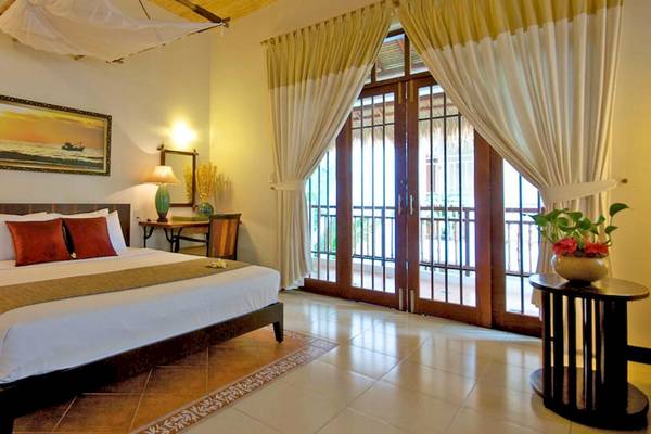 Schlafzimmer im Bamboo Village Beach Resort & Spa mit einem großen Bett, roten Kissen und zwei Lampen.