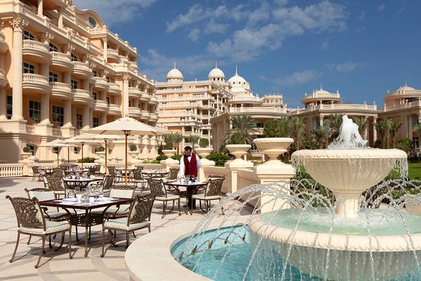 Außenbereich des Raffles The Palm Dubai mit einer Terrasse, einem Brunnen und gedeckten Tischen.