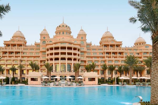 Außenansicht des Raffles The Palm Dubai Hotels mit Pool, Palmen und Sonnenschirmen