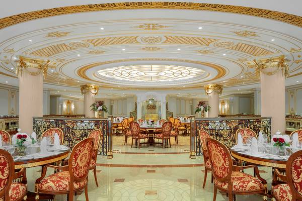 Innenansicht des Restaurants im Raffles The Palm Dubai mit golden verzierten Säulen und Decken.