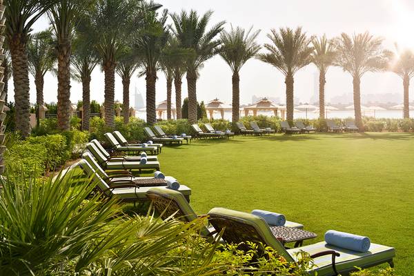 Terrasse im Raffles The Palm Dubai mit Liegen und Palmen