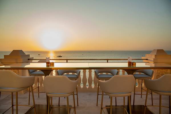 Terrasse des Raffles The Palm Dubai mit Stühlen und Meerblick beim Sonnenuntergang