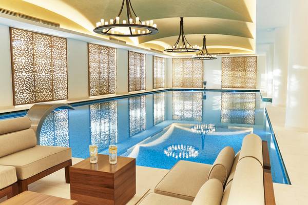 Innenpool im Raffles The Palm Dubai mit eleganten Möbeln und Kristallkronleuchtern.