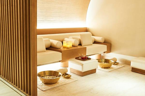 Spa-Behandlungsraum im Raffles The Palm Dubai mit weißen Möbeln, Holzelementen und Kerzen.