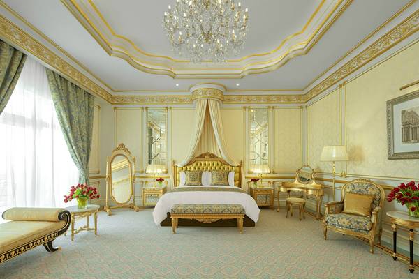 Schlafzimmer im Raffles The Palm Dubai mit goldenen Akzenten und Kristallkronleuchter.