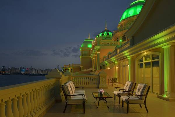 Beleuchtete Terrasse des Raffles The Palm Dubai bei Nacht mit Blick auf die Skyline