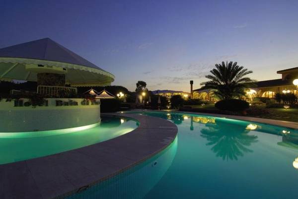 Nachtansicht des Außenpools des Baia Di Nora Hotels, beleuchtet und reflektiert im Wasser.