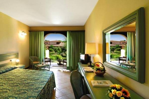 Hotelzimmer im Baia Di Nora mit Bett, Schreibtisch und Gartenblick