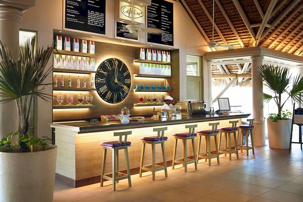 Innenansicht des Café Lux im LUX Belle Mare Resort & Villas mit Bar, Theke und Sitzgelegenheiten.