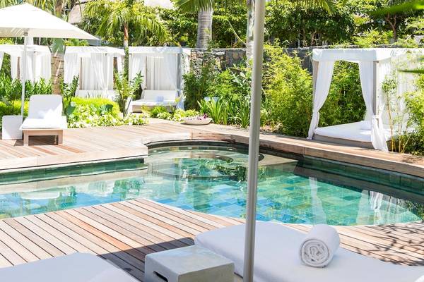 Pool-Lounge-Bereich im LUX Belle Mare Resort mit weißen Sonnenschirmen und Liegen.