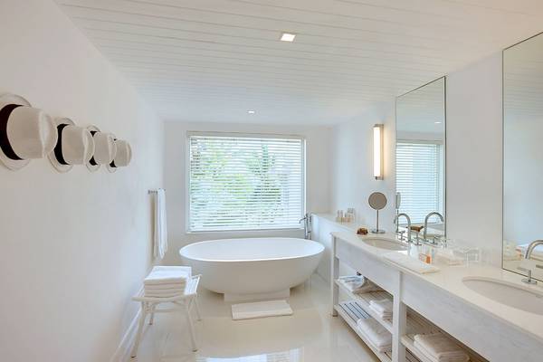 Das Badezimmer des LUX Belle Mare Resort & Villas mit Badewanne, Waschbecken und Spiegeln.